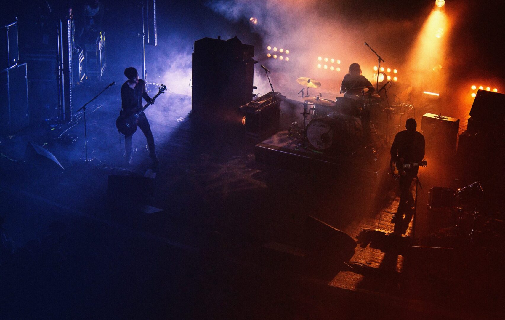 A band playing in the dark with lights on.